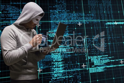 Cyber criminal is holding a credit card and a laptop against matrix code rain background