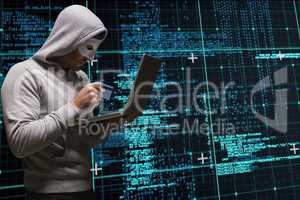 Cyber criminal is holding a credit card and a laptop against matrix code rain background