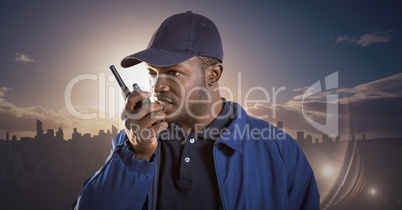 Security guard with walkie talkie against skyline and sunset