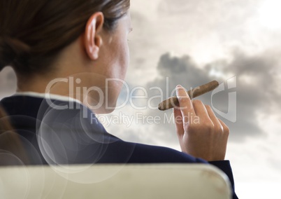 Over shoulder of seated business woman smoking cigar and looking at clouds with flare