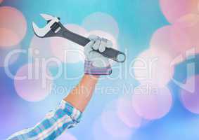 Hand holding wrench with sparkling light bokeh background