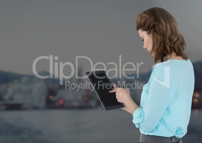 Businesswoman holding tablet with distant grey city background