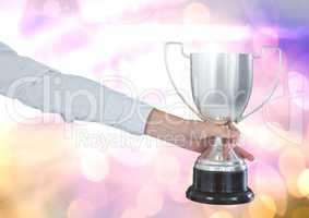 Hand with trophy and sparkling light bokeh background
