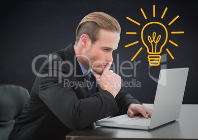 Business man thinking at laptop against navy background with yellow lightbulb