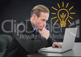 Business man thinking at laptop against navy background with yellow lightbulb
