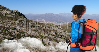 Hipster looking at mountains while standing on cliff against sky