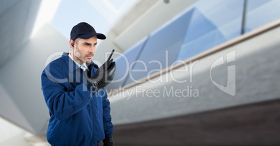 Security guard talking on walkie talkie while standing against defocused building