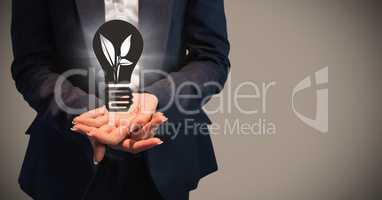 Business woman mid section with grey lightbulb graphic and flare in hands against brown background