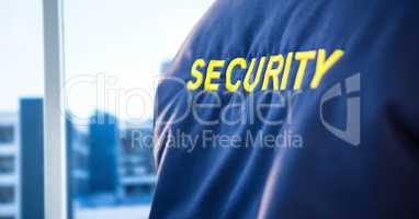 Back of security guard jacket against blurry window showing city