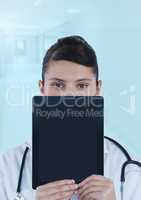 Doctor holding tablet over face in blue corridor