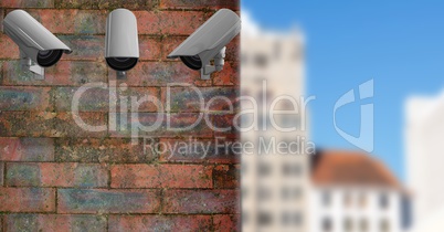 3 CCTV on a brick wall with the city in the background
