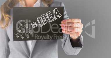 Business woman mid section with black card showing white idea doodle against grey background