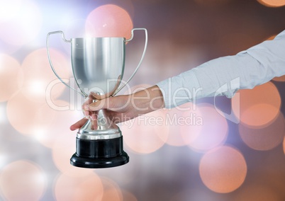 Hand holding trophy cup with sparkling light bokeh background