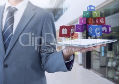 Businessman holding tablet with apps in shopping mall