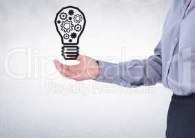 Business woman mid section with lightbulb graphic in hand against white wall