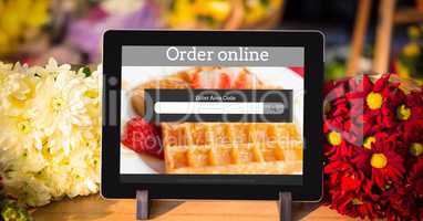 Digital tablet with waffle and text on screen surrounded by flowers