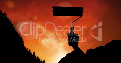 Silhouette image of hand holding paint roller against red sky