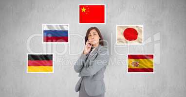 Businesswoman thinking while standing by flags against gray background