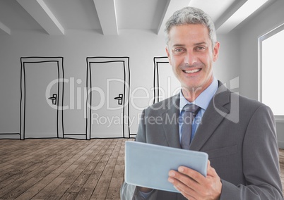 Smiling businessman holding digital tablet standing on hardwood floor against doors