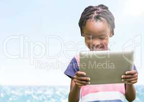 Boy with tablet against blurry water and flare