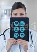 Doctor holding tablet with apps over face in corridor