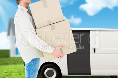 deliver is holding packages in order to load a car against garden background