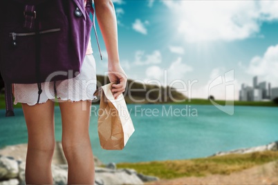 traveler holding backpack against a lake