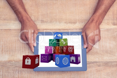 hands showing icons on the screen of one tablet computer against wooden background