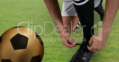 soccer player tying his shoes with golden ball