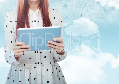Woman mid section with polka dot top and tablet against sky with flare