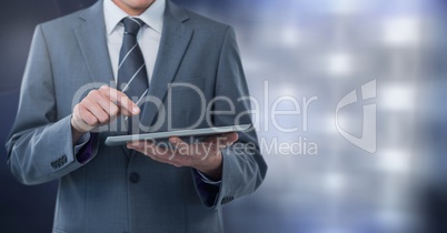 Businessman holding tablet with grey lights background