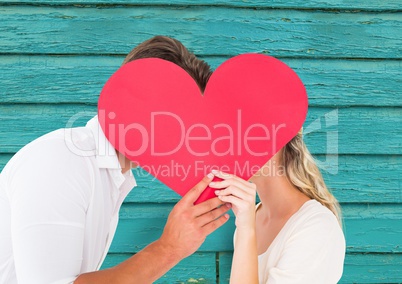 couple  kissing behind the heart with light blue wood background