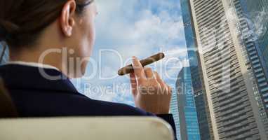 Rear view of businesswoman sitting on chair and looking at buildings while smoking cigar