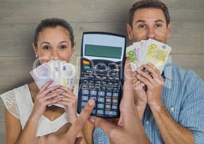 Cropped image of hands using calculator against couple holding currencies