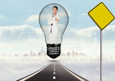 Digital composite image of smiling businesswoman in light bulb over road by signboard