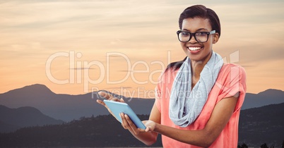 Hipster holding digital tablet while standing by mountains against sky