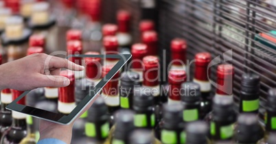 Hand taking picture of bottles through digital tablet at grocery shop