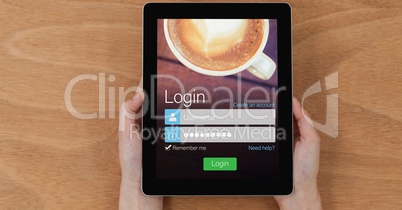 Directly above shot of hands holding digital tablet with login screen on wooden table
