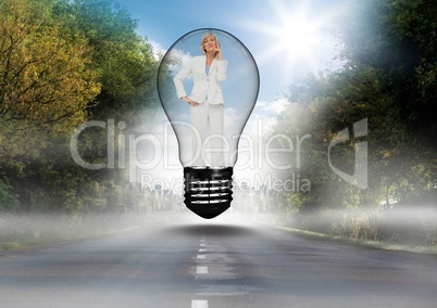 Thoughtful businesswoman standing in bulb over road against sky