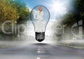 Thoughtful businesswoman standing in bulb over road against sky