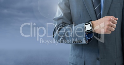 Businessman with watch against blue cloudy background