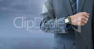 Businessman with watch against blue cloudy background
