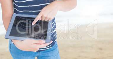 Woman mid section with tablet against blurry beach with flare