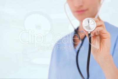 Woman doctor wearing blue blouse is holding a stethoscope against white background