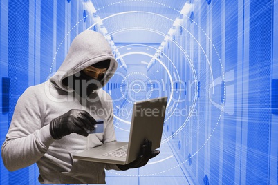 Cyber criminal is holding a credit card and a laptop against database background