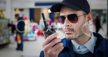 Security guard with walkie talkie against blurry shopping centre