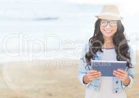 Trendy woman with tablet against blurry beach with flare