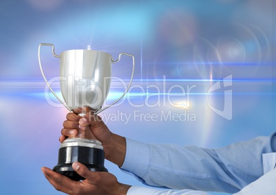 business hand with trophy, blue background whit flares