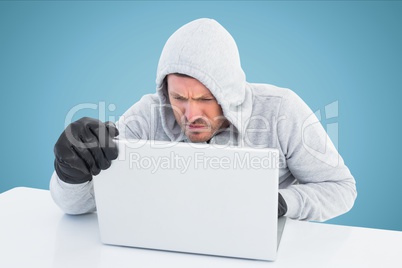 Hacker using laptop in office with blue background