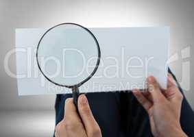 Magnifying glass in hands looking at paper